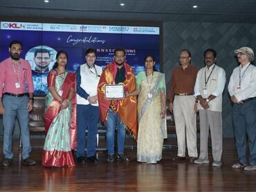 Two men in bicycle jerseys sitting outside at table having coffee