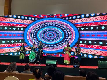Two men in bicycle jerseys sitting outside at table having coffee